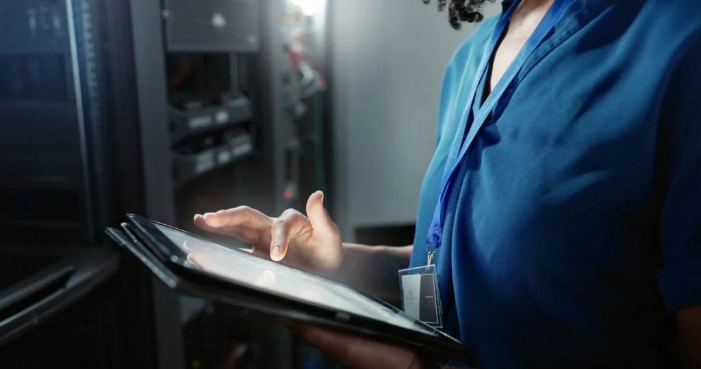 Technicien Habyss supervisant une infrastructure réseau via tablette en salle serveur